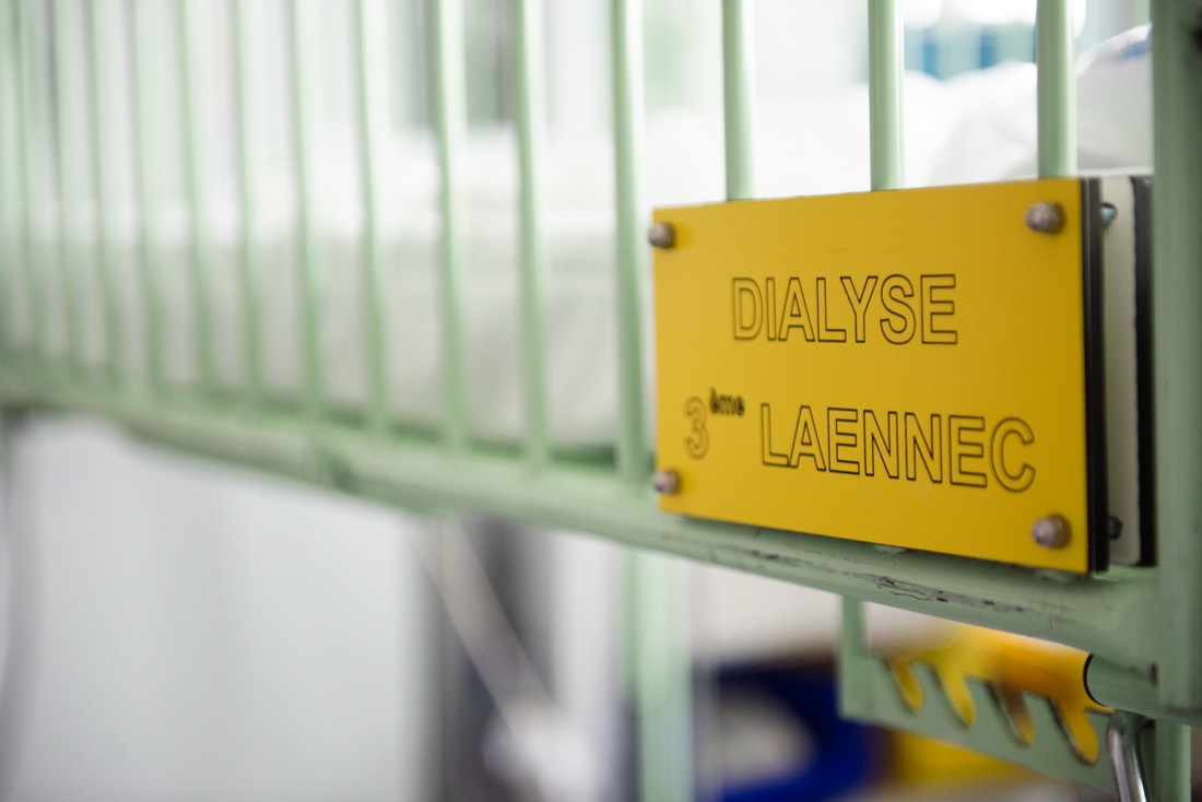 Plaque « Dialyse 3ème Laennec » fixée sur un lit à barreaux vert.